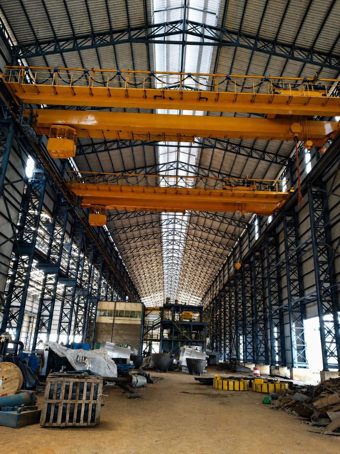Two yellow overhead EOT cranes spanning a long heavy-engineering bay