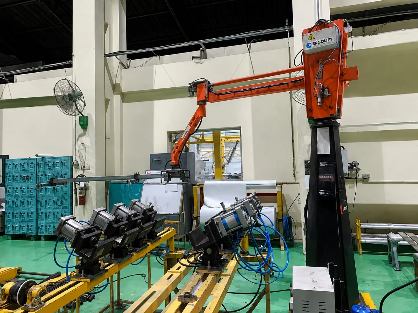 Orange Ergolift manipulator above a row of electric motors on an assembly fixture line