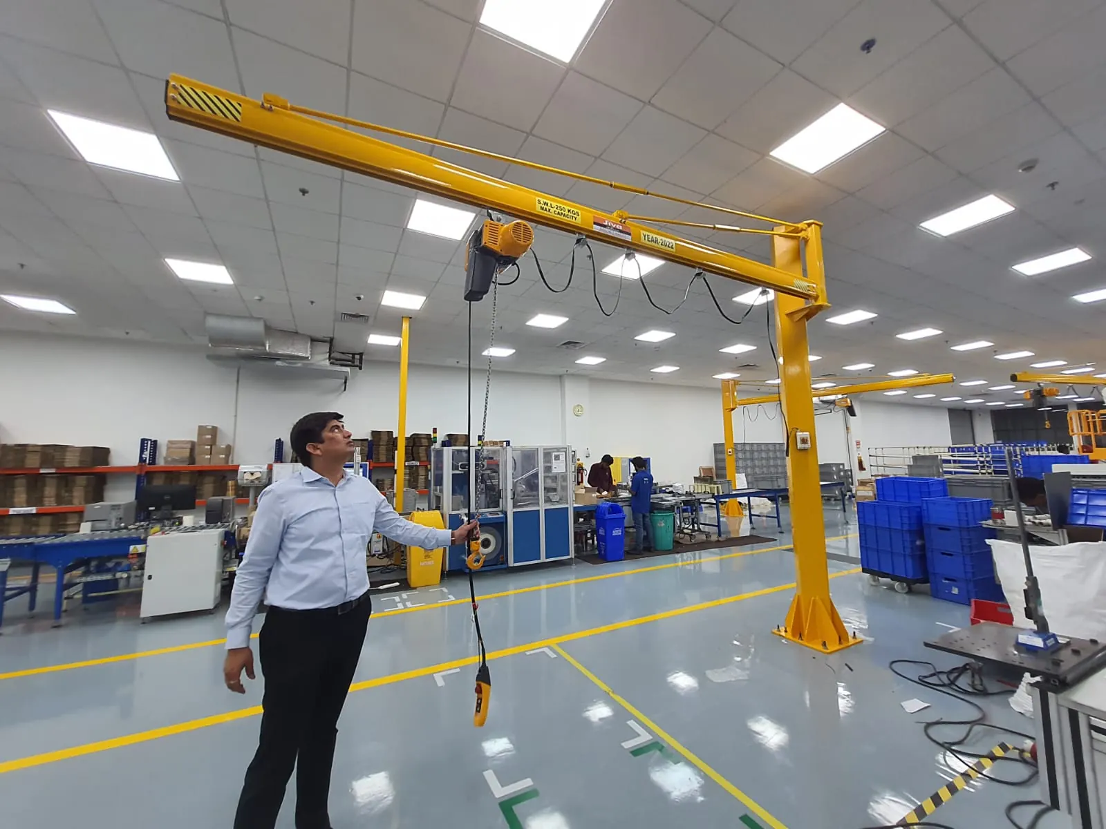 Engineer operating a yellow jib crane with a pendant control