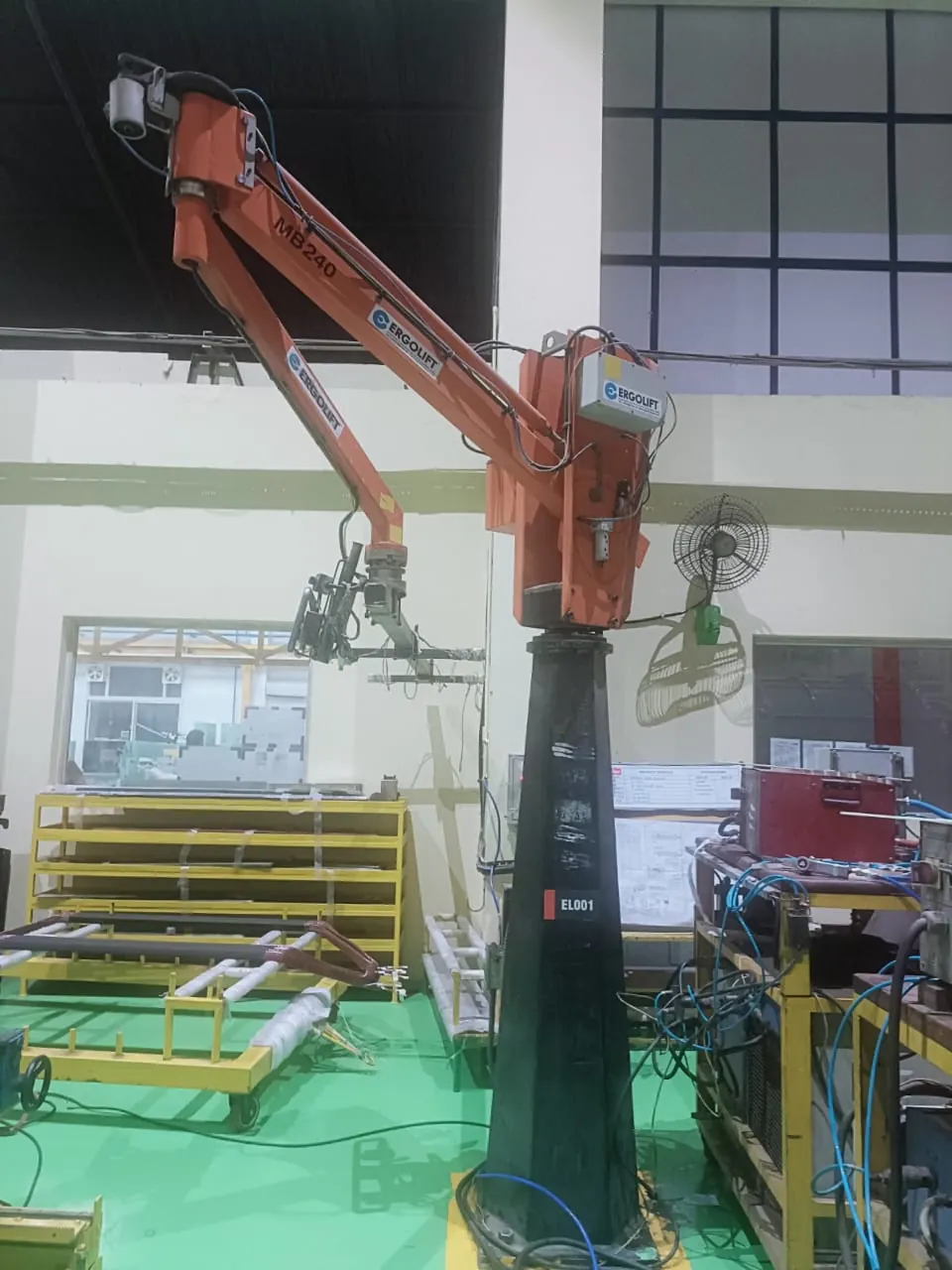 Orange manipulator arm handling sheets beside a work table