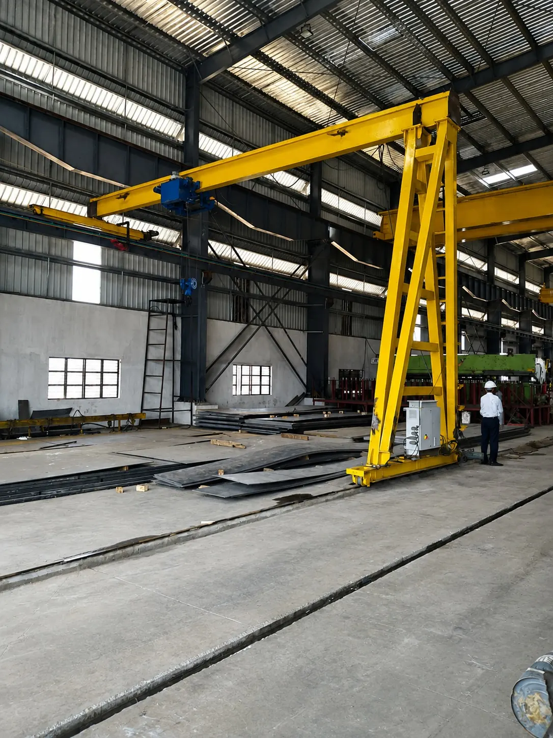 Yellow semi-gantry crane spanning a steel plate storage bay