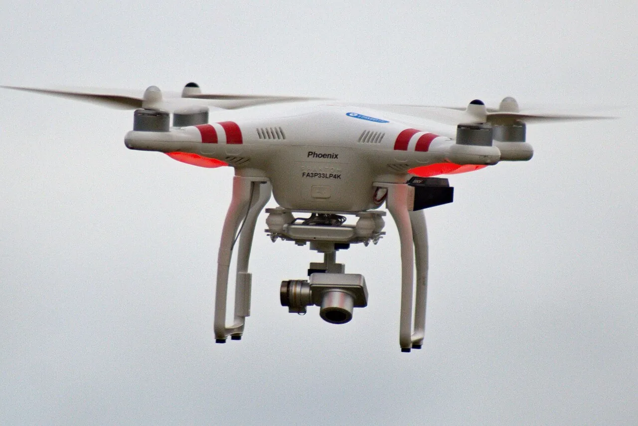 White quadcopter drone with camera gimbal in flight