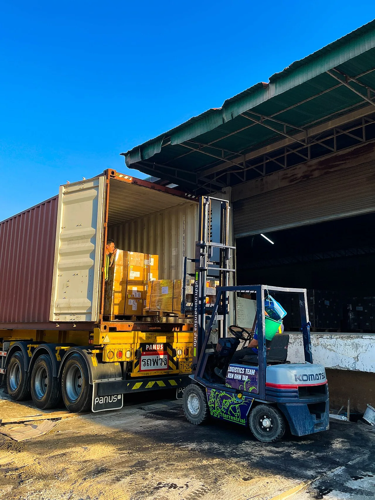 Forklift loading a shipping container at a warehouse dock