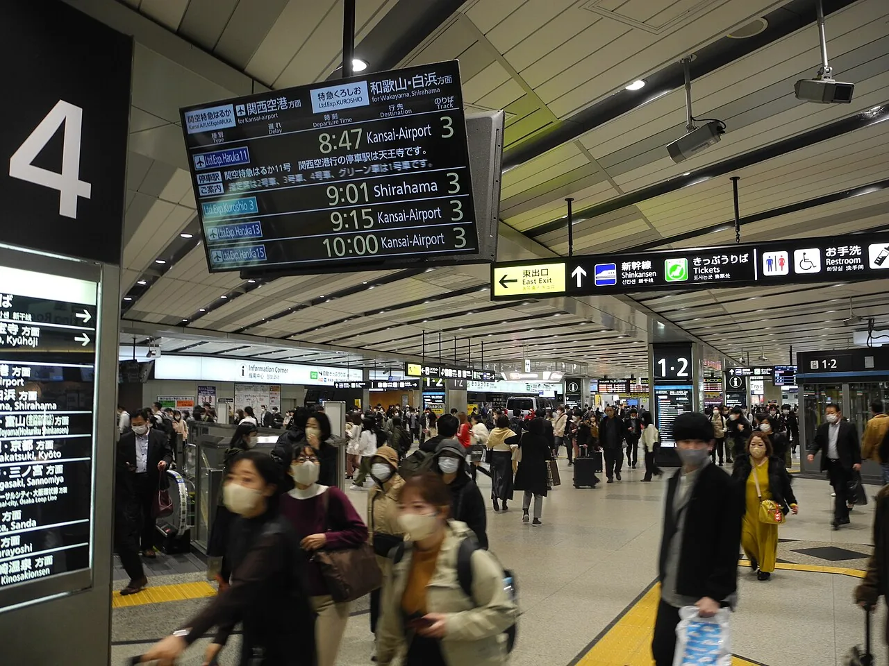Crowd of commuters walking through a busy railway station concourse